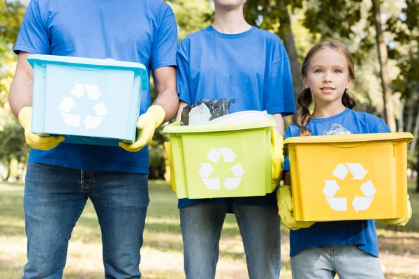 Família de ativistas segurando recipientes com símbolos de reciclagem, cheios de lixo plástico, conceito de ecologia — Fotografia de Stock