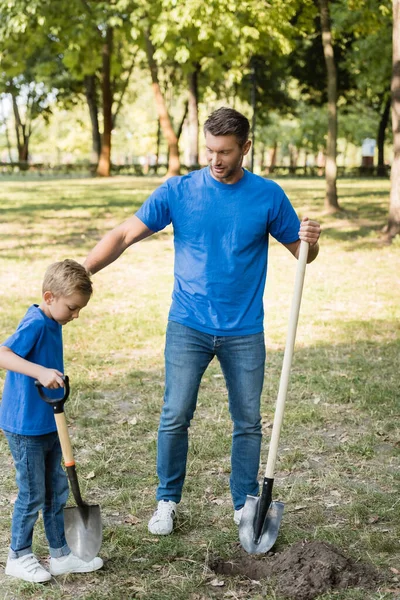 Father and son digging ground in forest with shovels, ecology concept — Stock Photo