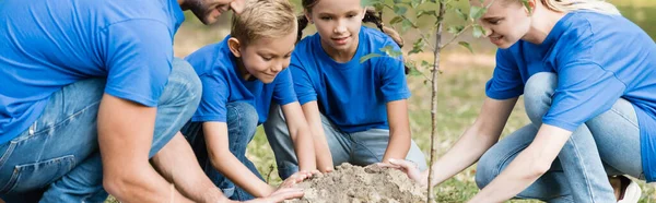 Parents and two children planting young tree in forest, ecology concept, banner — Stock Photo