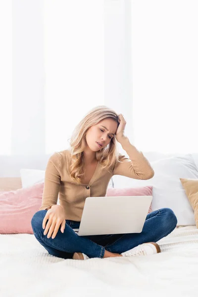 Tired teleworker looking at laptop on bed — Stock Photo