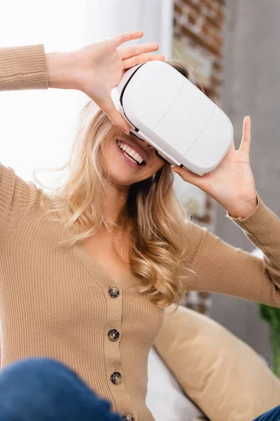 Mujer alegre usando auriculares de realidad virtual en casa - foto de stock