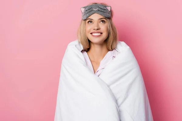 Mulher sorridente de olhos vendados e cobertor olhando para cima no fundo rosa — Fotografia de Stock