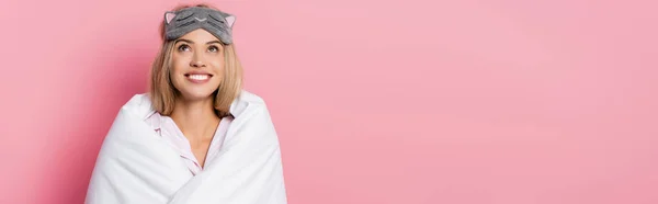 Young woman in blindfold and blanket looking up on pink background, banner — Stock Photo