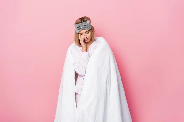Sleepy woman in blindfold and blanket standing on pink background — Stock Photo
