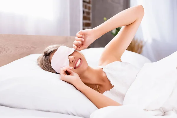 Веселая женщина с повязкой на глазах на кровати по утрам — стоковое фото