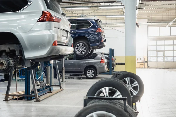 Modern workshop with automobiles raised on car lifts on blurred foreground — Stock Photo