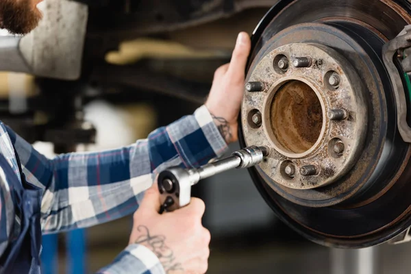 Partial view of repairman adjusting wheel hub with wrench on blurred foreground — Stock Photo