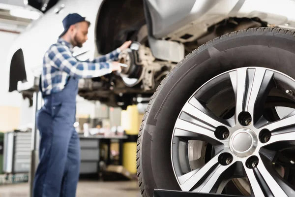 Close up view of wheel near mechanic repairing wheel hub on blurred background — Stock Photo