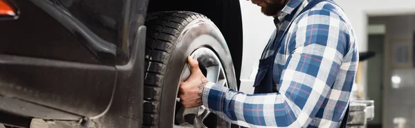 Cropped view of mechanic fixing wheel on car, banner — Stock Photo
