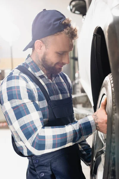 Junger Techniker justiert Rad am Auto in Werkstatt — Stockfoto