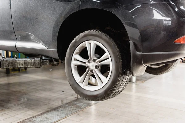 Rodas dianteiras do carro moderno levantado na oficina para manutenção — Fotografia de Stock