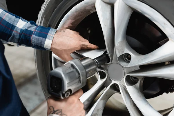 Partial view of technician fixing wheel on car with pneumatic wrench — Stock Photo