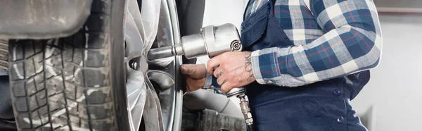 Vue partielle de la roue de fixation du technicien sur l'automobile avec clé pneumatique, bannière — Photo de stock