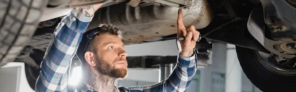 Mechanic examining bottom of lifted automobile, banner — Stock Photo