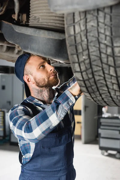 Young technician adjusting wheel on car on blurred foreground — Stock Photo