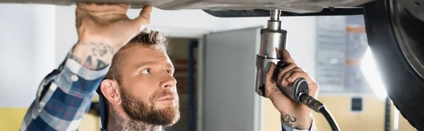 Repairman fixing car detail with pneumatic wrench, banner — Stock Photo