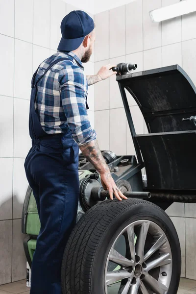 Mechaniker überprüft Rad an Auswuchtmaschine in Werkstatt — Stockfoto