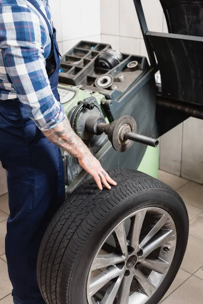 Cropped view of technician checking wheel on balance control machine in workshop — Stock Photo