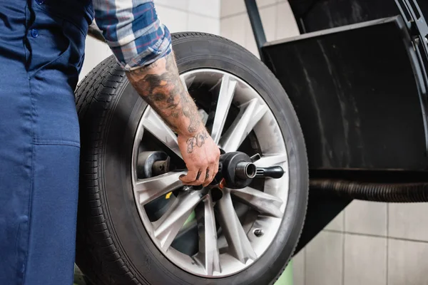 Vista ritagliata del riparatore che mette la ruota sulla macchina di controllo dell'equilibrio in officina — Foto stock