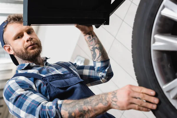 Low angle view of technician examining wheel on balance control equipment on blurred foreground — Stock Photo