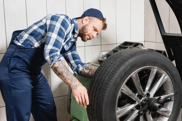 Young mechanic checking wheel on balance control machine — Stock Photo