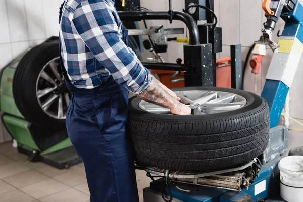 Cropped view of mechanic putting wheel on tire replacement machine in workshop — Stock Photo