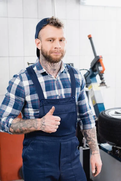 Young mechanic in workwear showing thumb up while looking at camera — Stock Photo
