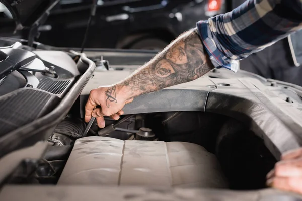 Partial view of workman checking level of engine oil on blurred foreground — Stock Photo