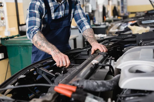 Ausgeschnittene Ansicht des Mechanikers bei der Überprüfung des Motorraums in der Werkstatt im unscharfen Vordergrund — Stockfoto