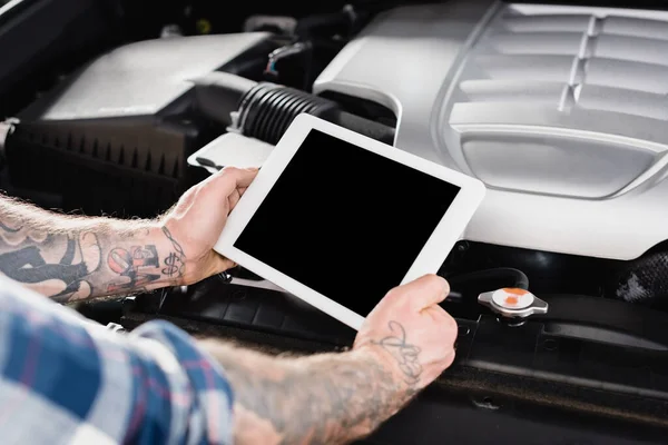 Cropped view of mechanic with tablet making diagnostic of car near engine compartment on blurred foreground — Stock Photo