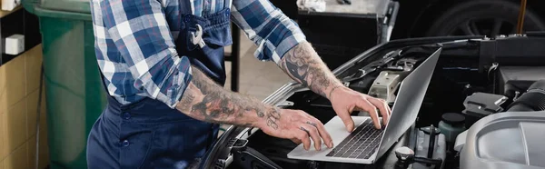 Partial view of workman making diagnostic of car engine compartment with laptop, banner — Stock Photo