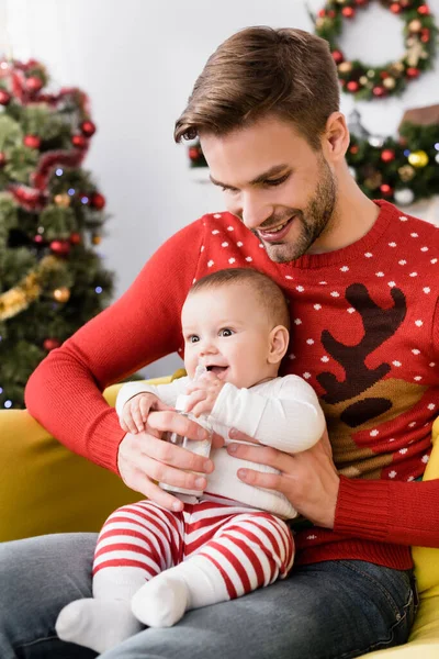 Felice uomo che alimenta il figlio neonato mentre tiene in mano il biberon con latte materno — Foto stock