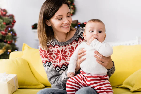 Femme gaie en pull tenant dans les bras enfant fils — Photo de stock