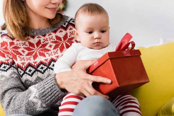 Mutter hält verpacktes Weihnachtsgeschenk in der Nähe ihres kleinen Sohnes — Stockfoto