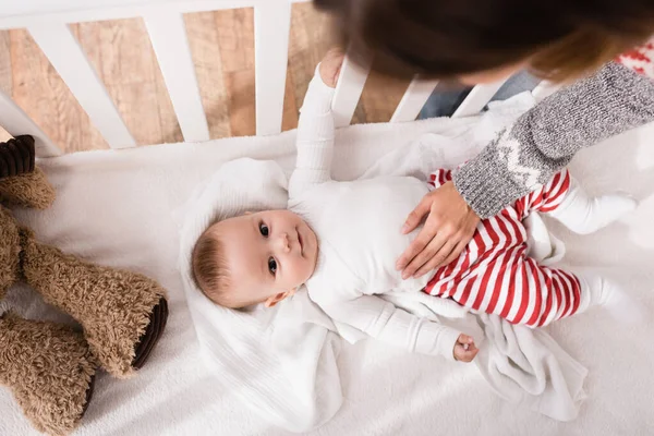 Vue de dessus de la mère près du petit garçon couché dans la crèche de bébé — Photo de stock