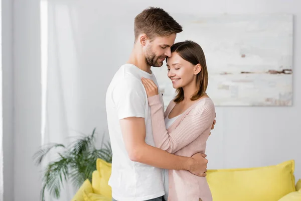 Feliz hombre abrazando alegre esposa en casa - foto de stock