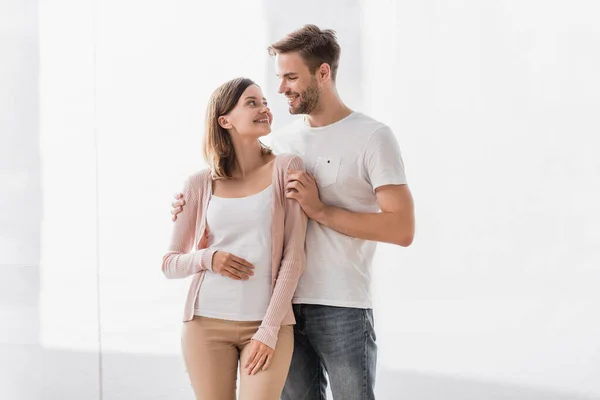 Fröhlicher Mann und Frau, die sich beim Umarmen zu Hause anschauen — Stockfoto