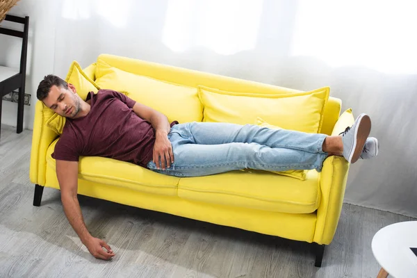 Giovane uomo che dorme sdraiato sul divano a casa — Foto stock