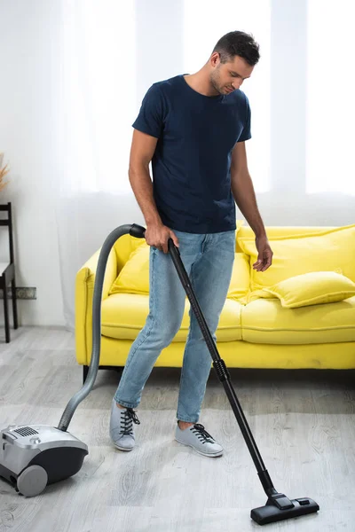 Homem usando aspirador durante o trabalho doméstico na sala de estar — Fotografia de Stock