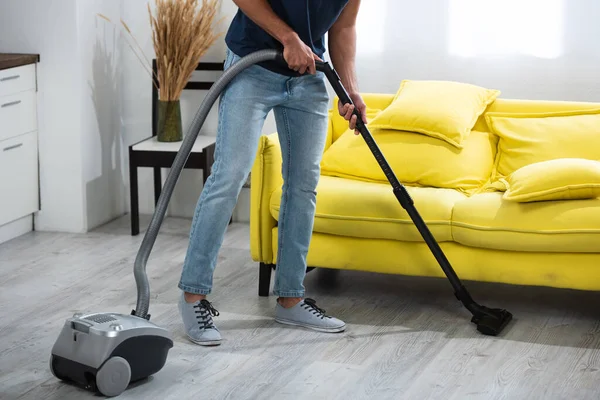 Cropped view of man cleaning floor with vacuum cleaner at home - foto de stock