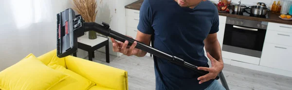 Cropped view of man having fun with brush of vacuum cleaner at home, banner - foto de stock