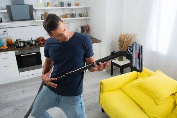 Jeune homme regardant brosse de l'aspirateur à la maison — Photo de stock