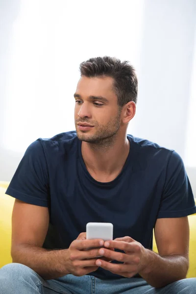 Young man looking away while using smartphone on blurred foreground — Stock Photo