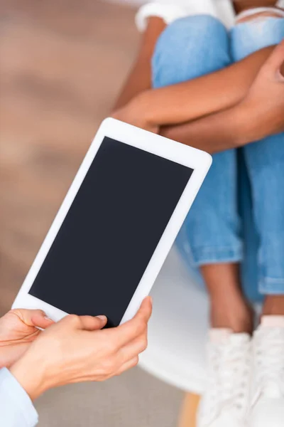 Vista ritagliata di psicologo con tablet digitale vicino offuscata ragazza afroamericana su sfondo — Foto stock