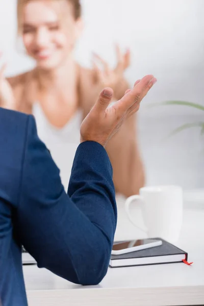 Close up view of businessman gesturing, while sitting at table on blurred background — Stock Photo