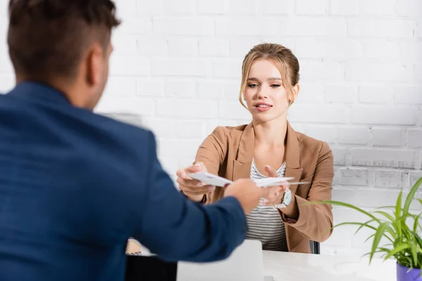 Esecutivo femminile che prende i documenti dal collega, mentre siede al tavolo in carica su primo piano sfocato — Foto stock