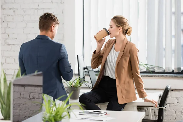 Back view of businessman standing near female colleague drinking coffee during break in office — Stock Photo