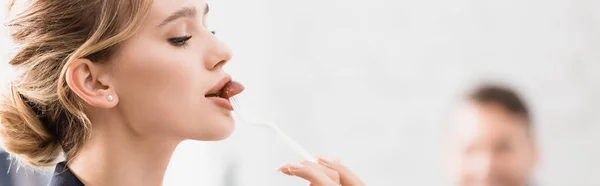 Businesswoman eating with plastic fork during break in office on blurred background, banner — Stock Photo