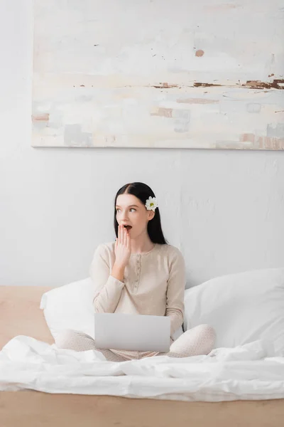 Schockierte Freelancer mit Vitiligo Blick weg in der Nähe von Laptop im Schlafzimmer — Stockfoto