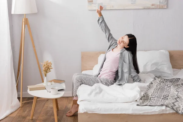Happy woman with vitiligo stretching while sitting in bedroom — Stock Photo